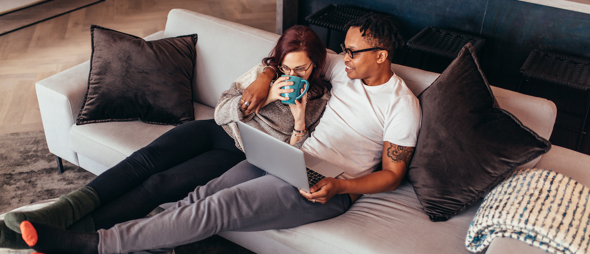 Couple relaxing on their couch looking at laptop.