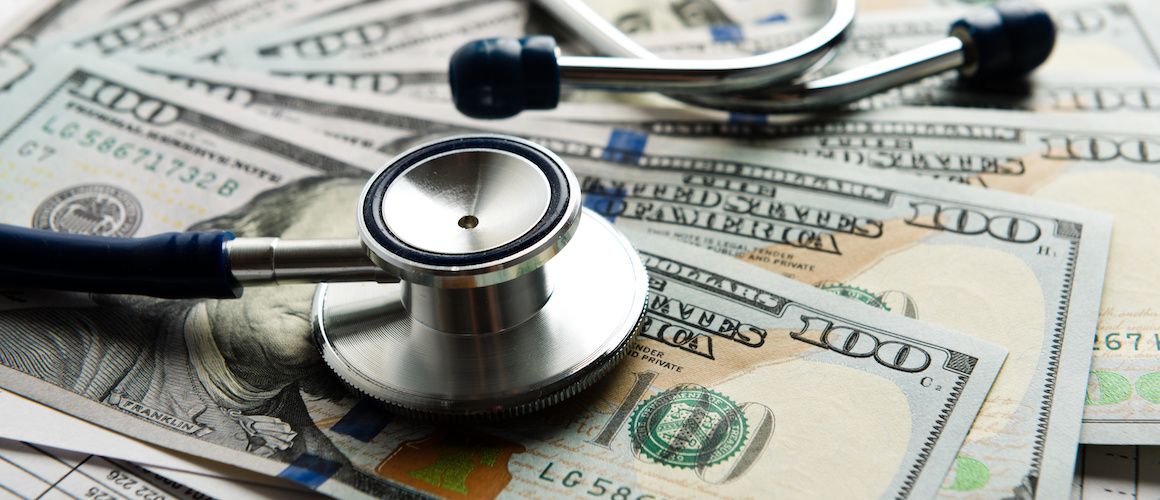 Stethoscope laying on hundred dollar bills