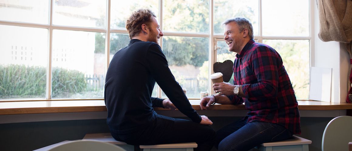 Two men sitting at a coffee shopping discussing the history of credit in America.