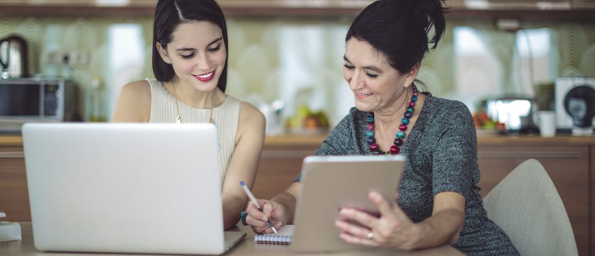 Mother and daughter their shared kitchen looking at technology.